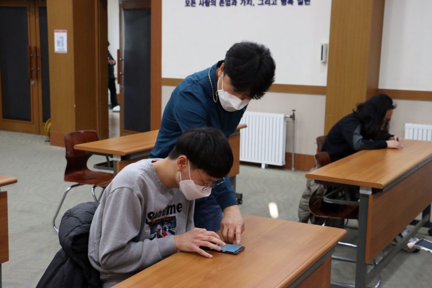 우리복지관 직원이 1:1로 스마트폰을 가리키며 설명하고 있는 모습