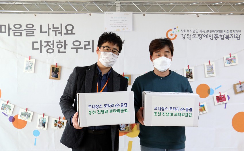 지역복지지원팀 이선근 팀장과 르네상스 로타리 클럽 홍천 진달래 로타리클럽회원이 빵 간식이 들어있는 박스를 들고있는 사진