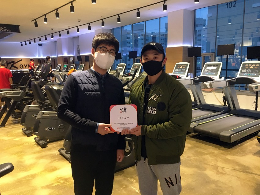 현판을 함께 들고있는 jk gym대표와 우리복지관 이선근 팀장