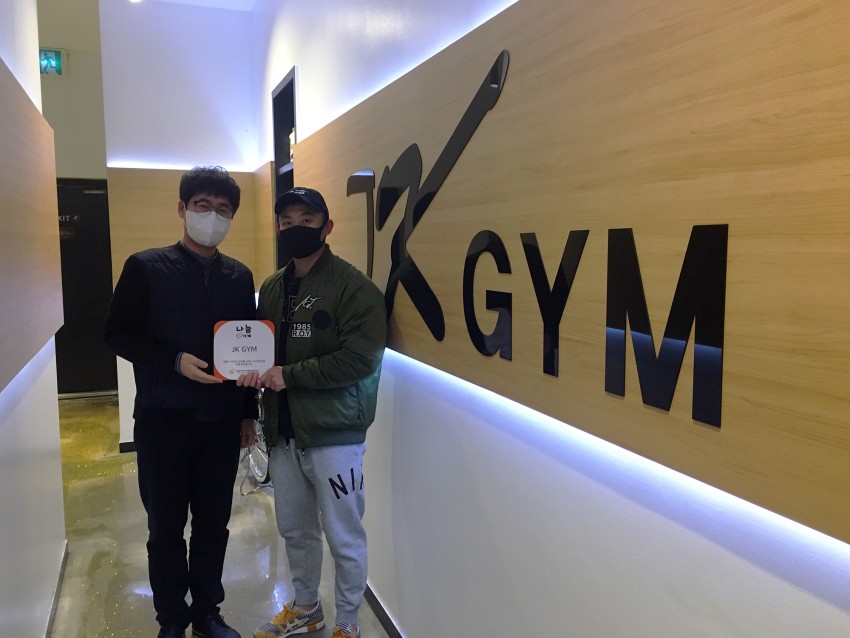 현판을 함께 들고있는 jk gym대표와 우리복지관 이선근 팀장