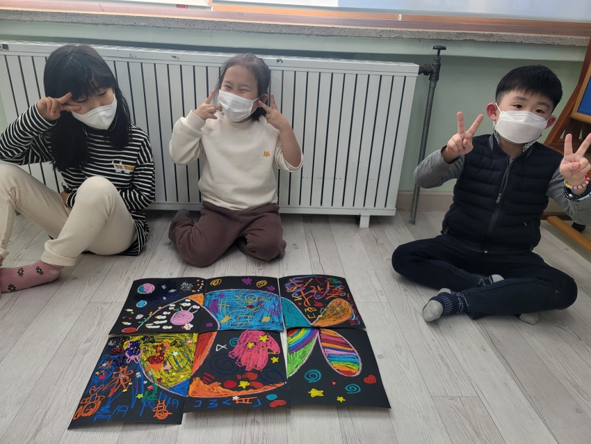 완성된 미술작품 앞에서 포즈를 취하는 아이들